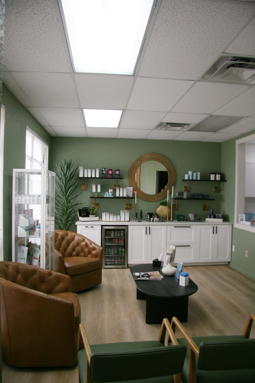 The Bespoke lounge — leather chairs, the product wall under the round mirror, and the sage waiting area where patients settle in before a visit